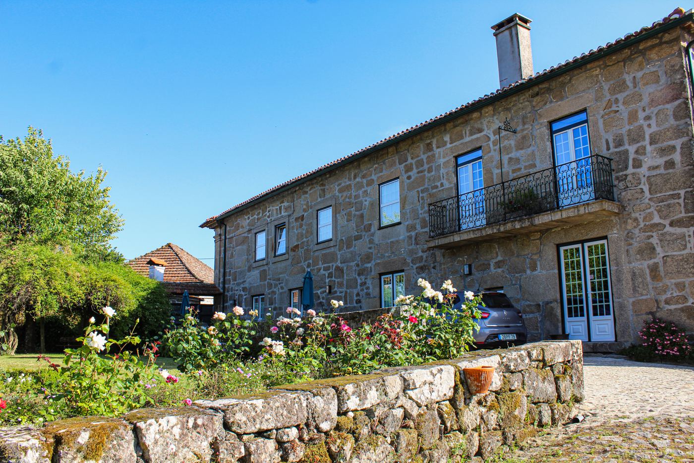 Fachada de granito com roseiras e varanda de ferro