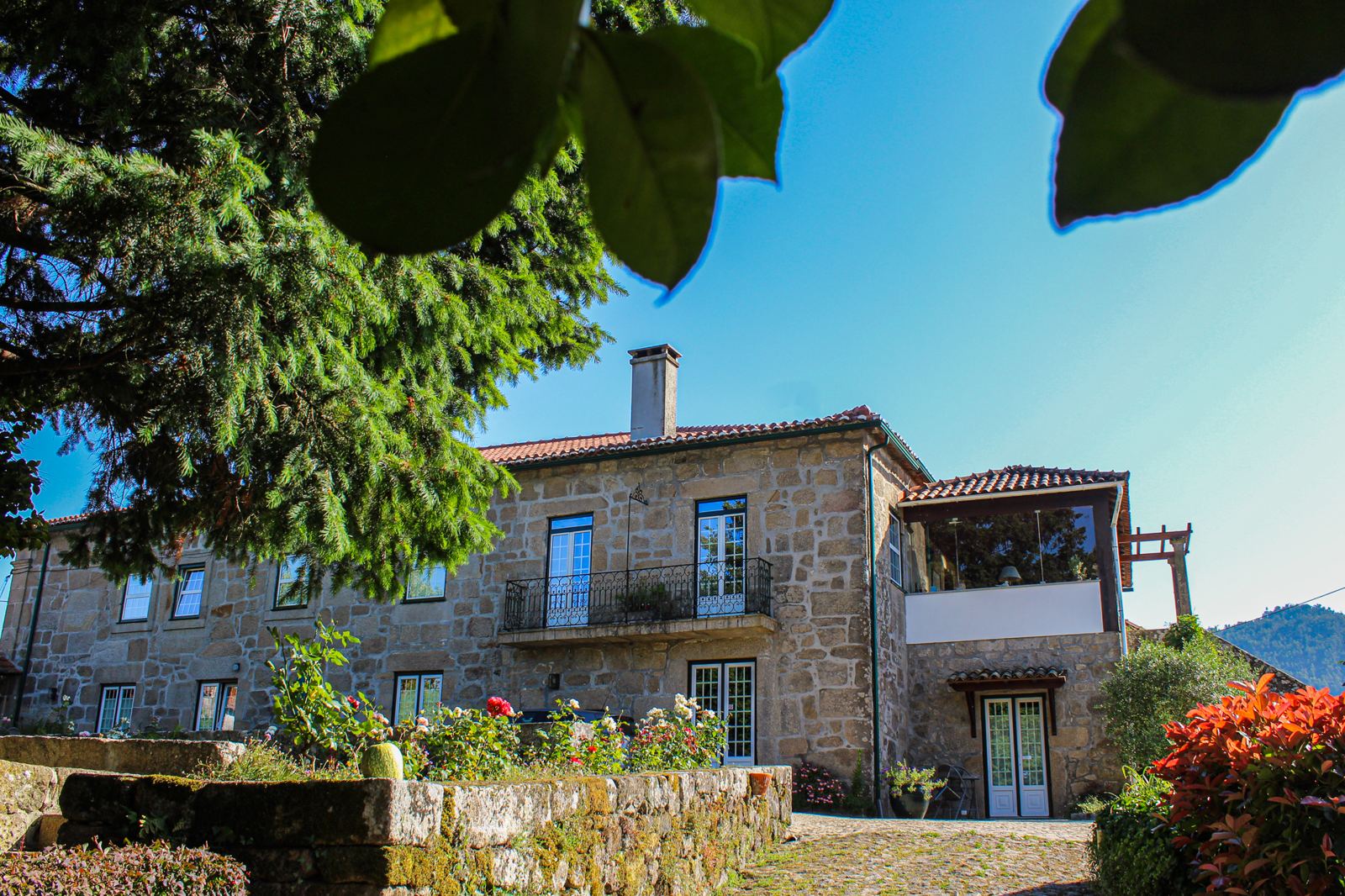 Fachada de granito da Casa de Fataunços, com roseiras e varanda